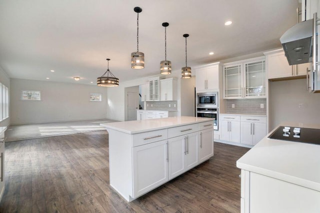 kitchen with dark wood-style floors, a kitchen island, decorative backsplash, appliances with stainless steel finishes, and wall chimney range hood