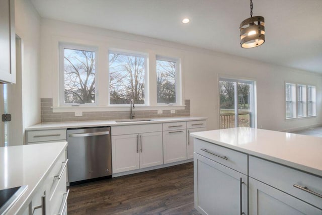 kitchen with tasteful backsplash, dark wood finished floors, light countertops, stainless steel dishwasher, and a sink