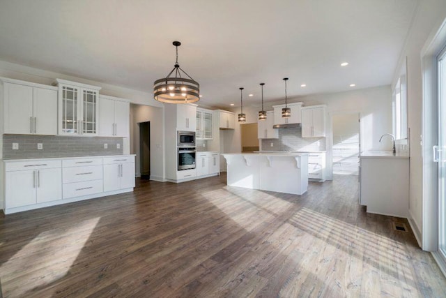 kitchen featuring dark wood-style flooring, white cabinets, glass insert cabinets, appliances with stainless steel finishes, and tasteful backsplash