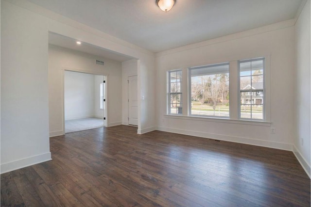 spare room with dark wood-style floors, visible vents, and baseboards