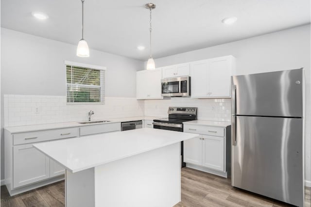 kitchen with appliances with stainless steel finishes, wood finished floors, light countertops, and a sink