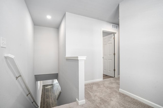 hall with visible vents, an upstairs landing, carpet floors, and baseboards