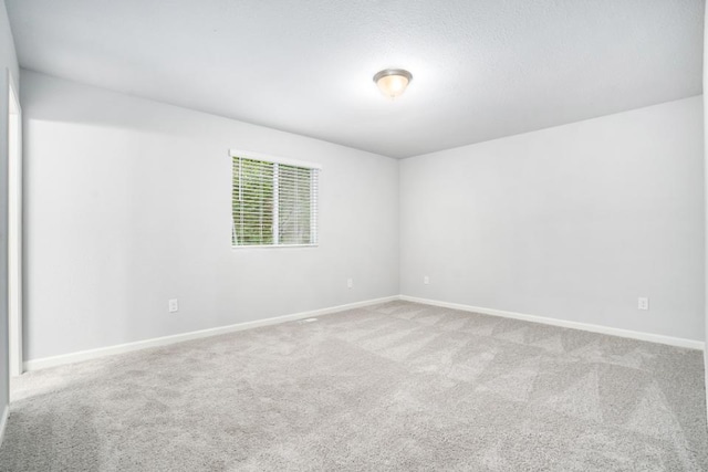 carpeted spare room featuring baseboards