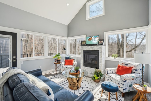 living room with baseboards, high vaulted ceiling, and a fireplace