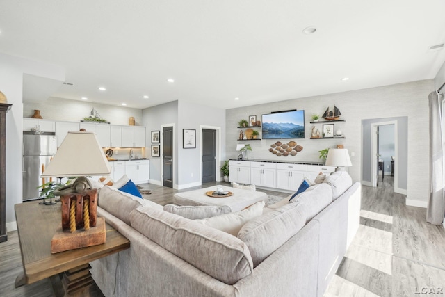 living room featuring recessed lighting, baseboards, and light wood-style flooring