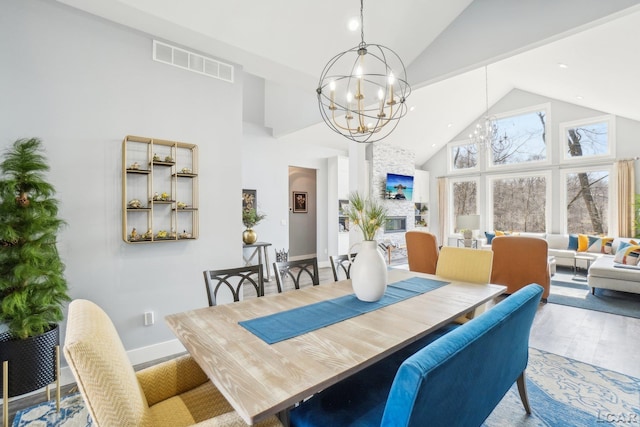 dining room with wood finished floors, baseboards, visible vents, high vaulted ceiling, and an inviting chandelier