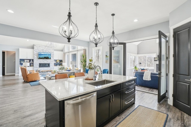 kitchen with open floor plan, dishwasher, an island with sink, and a sink