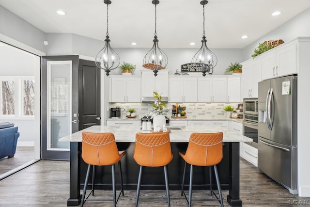 kitchen featuring dark wood-type flooring, decorative light fixtures, decorative backsplash, appliances with stainless steel finishes, and white cabinets