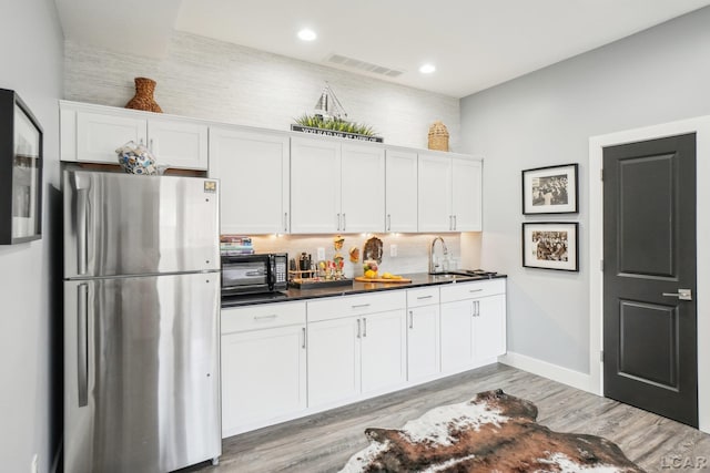 kitchen with dark countertops, visible vents, white cabinetry, and freestanding refrigerator