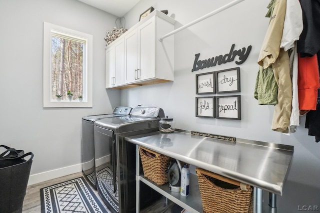 laundry area featuring washing machine and clothes dryer, cabinet space, baseboards, and wood finished floors