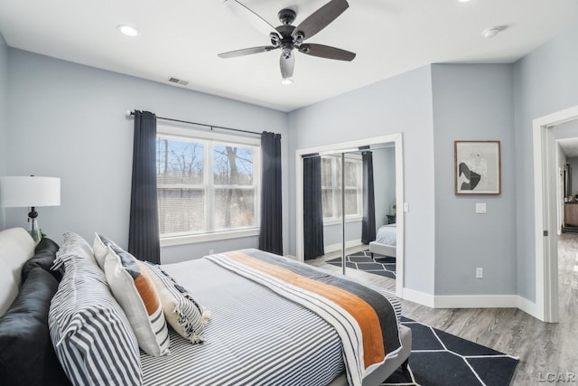 bedroom with wood finished floors, visible vents, baseboards, recessed lighting, and a closet