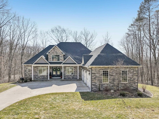 view of front of property with concrete driveway, a front yard, french doors, a garage, and stone siding