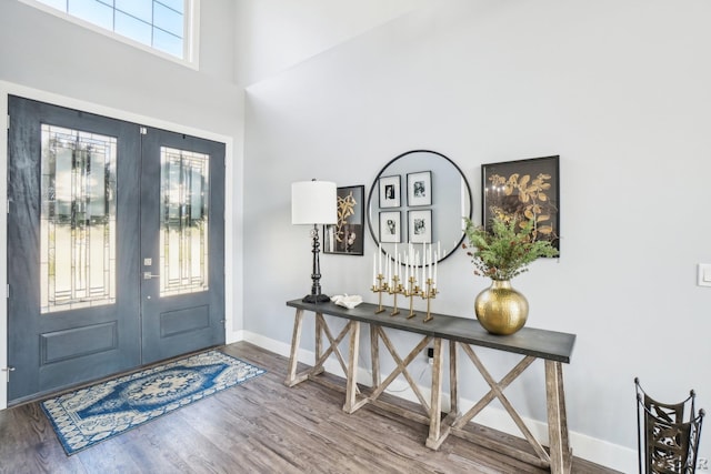 entrance foyer featuring wood finished floors, a high ceiling, french doors, and baseboards