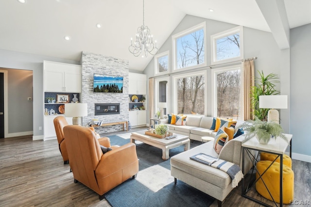 living room with baseboards, a chandelier, a fireplace, wood finished floors, and high vaulted ceiling