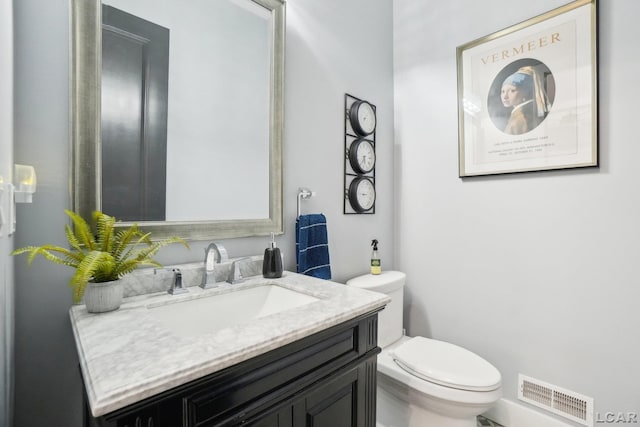 half bath with visible vents, toilet, and vanity