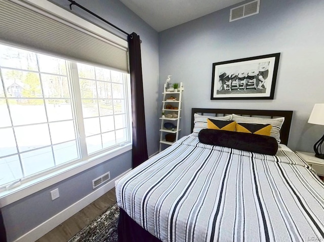 bedroom with dark wood finished floors, visible vents, and baseboards