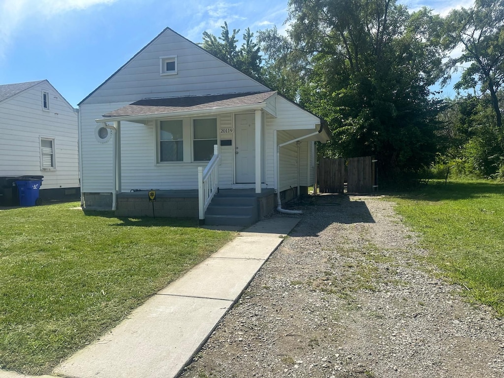 bungalow with a porch, driveway, a front yard, and fence