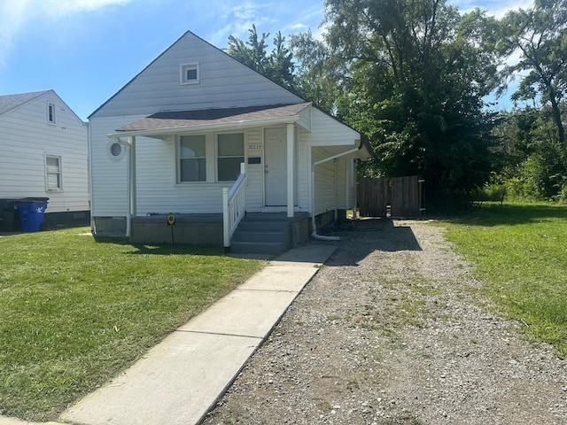 bungalow with a porch, driveway, a front yard, and fence