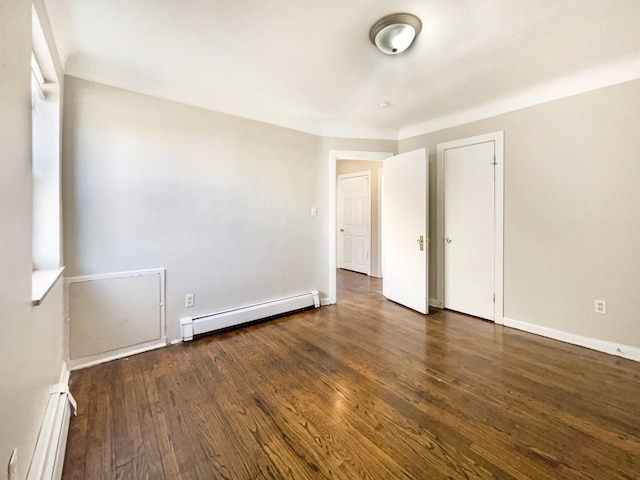 spare room with wood finished floors, baseboards, and baseboard heating