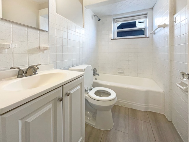 full bath with toilet, wood finished floors, tile walls, tub / shower combination, and vanity