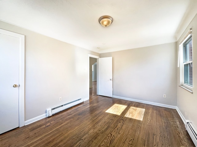 spare room with a baseboard radiator, baseboards, baseboard heating, and dark wood-style floors