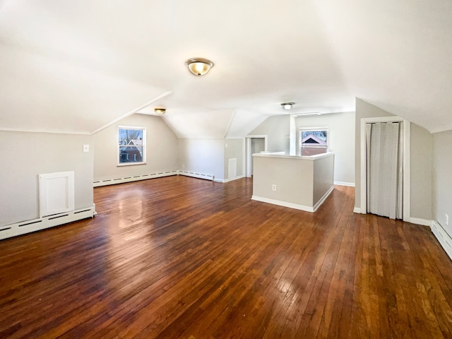 additional living space with vaulted ceiling, a baseboard heating unit, baseboards, and hardwood / wood-style flooring