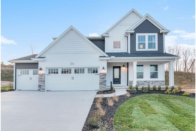 view of front of property featuring an attached garage, concrete driveway, a front lawn, stone siding, and board and batten siding