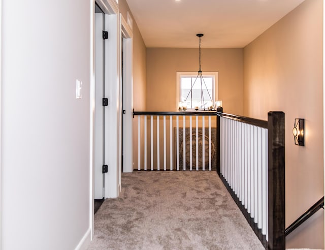 hall with an upstairs landing, carpet, and an inviting chandelier