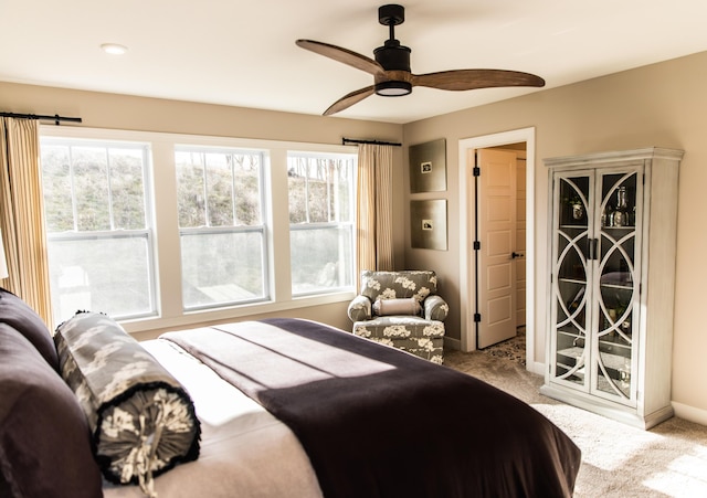 carpeted bedroom featuring multiple windows, a ceiling fan, and baseboards