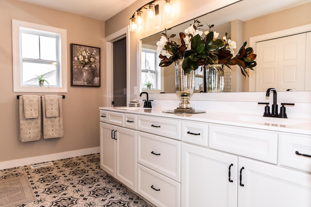 bathroom with double vanity, visible vents, baseboards, and a sink