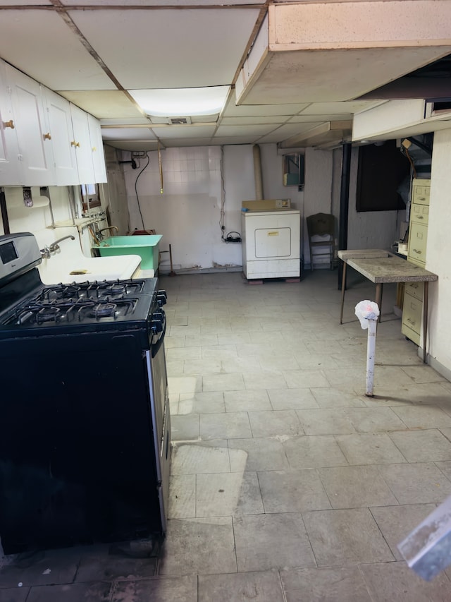 interior space featuring gas stove, washer / clothes dryer, white cabinetry, and a sink