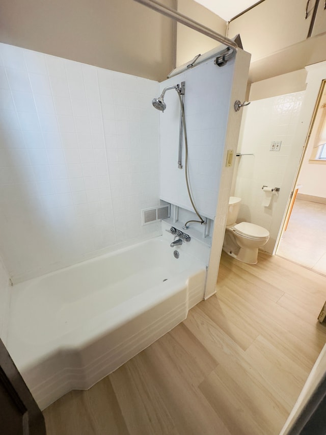 bathroom with visible vents, toilet, bathing tub / shower combination, and wood finished floors