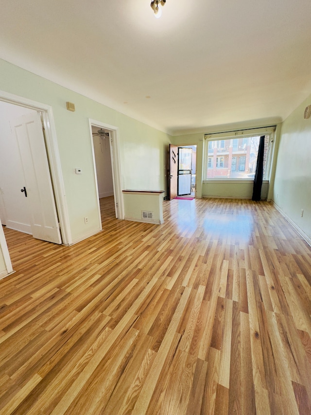 unfurnished living room with light wood finished floors, visible vents, and baseboards