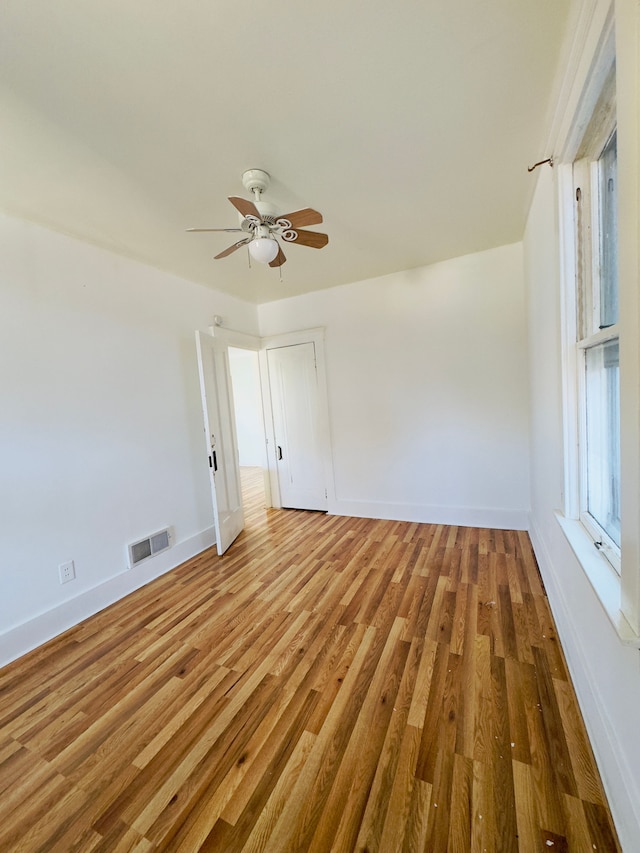 spare room with baseboards, wood finished floors, visible vents, and ceiling fan