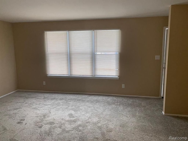 unfurnished room with baseboards and carpet