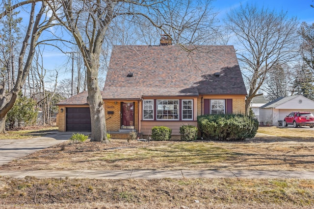 cape cod home with a garage, brick siding, a chimney, and driveway