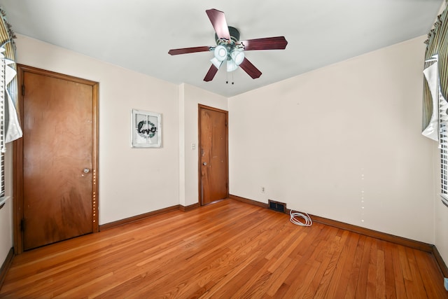 empty room with visible vents, baseboards, light wood-style floors, and a ceiling fan