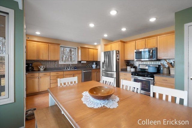 kitchen with a sink, stainless steel appliances, light wood-type flooring, and tasteful backsplash