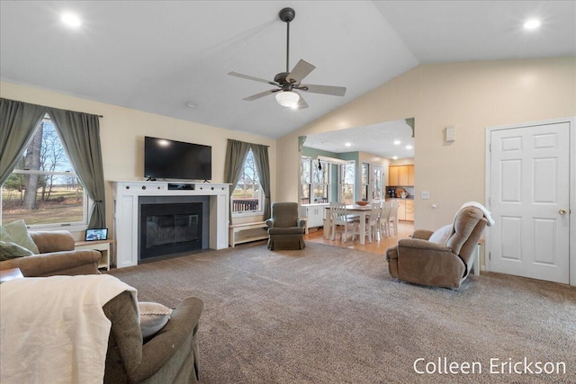 living room with a glass covered fireplace, carpet, a wealth of natural light, and ceiling fan