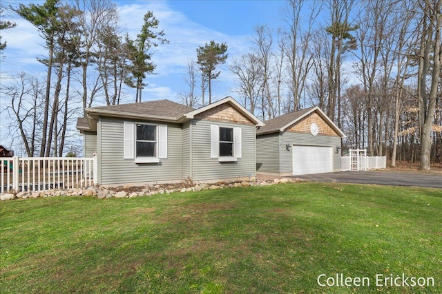 view of front facade with a front yard, an outdoor structure, an attached garage, and driveway