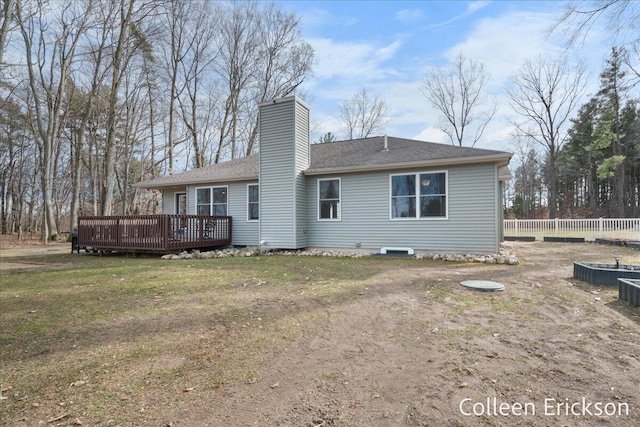 rear view of house featuring a wooden deck, a yard, a chimney, and fence