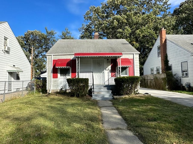 bungalow featuring cooling unit, a shingled roof, a front yard, and fence