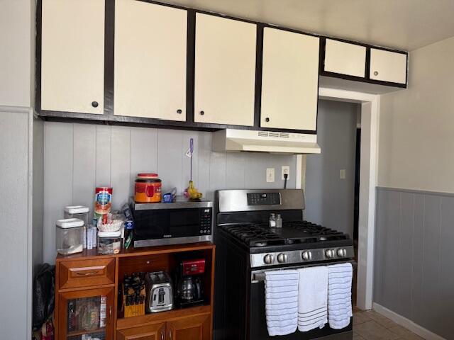 kitchen with white cabinetry, wainscoting, under cabinet range hood, and stainless steel appliances