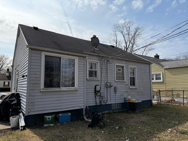 rear view of house featuring central air condition unit and fence