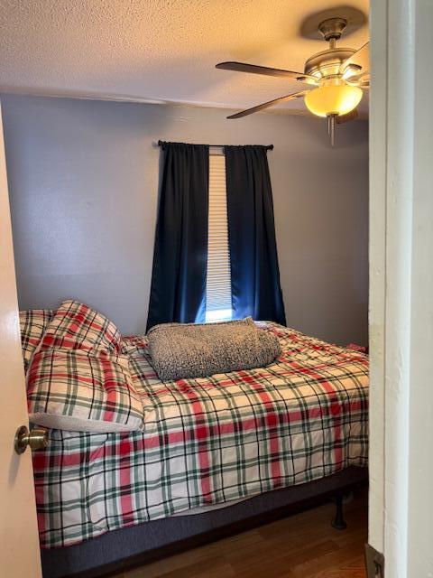 bedroom featuring ceiling fan, a textured ceiling, and wood finished floors