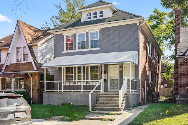 american foursquare style home featuring brick siding and a porch