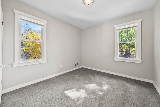 carpeted empty room featuring visible vents and baseboards