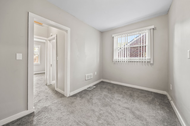 carpeted empty room with visible vents and baseboards