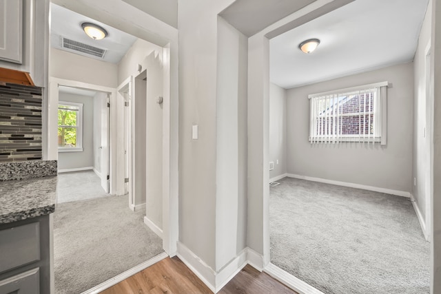 corridor featuring baseboards, visible vents, and carpet floors