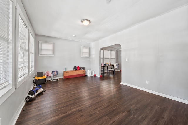 interior space with wood finished floors, arched walkways, and baseboards